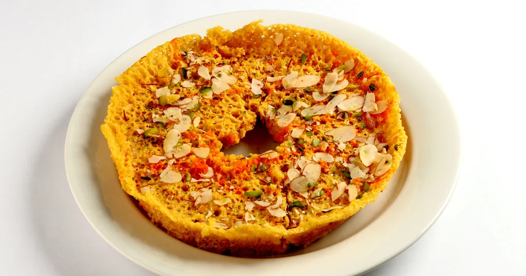 Assorted traditional Rajasthani sweet dishes including Ghewar, Malpua, Balushahi, and Rabri served in authentic style